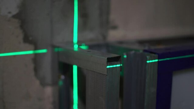 Laser building level with green beans is shines on the metal construction for marking a flat surface.