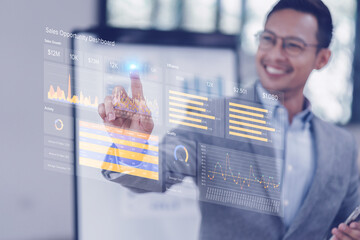 Businessman uses an interactive digital dashboard to analyze sales data and performance metrics in a modern office.