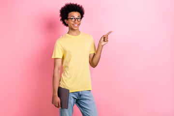 Portrait of nice young man hold laptop direct finger empty space wear yellow t-shirt isolated on pink color background