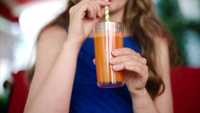 Woman in a blue dress drinking a carrot juice at a restaurant terrace