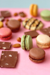 Pastel macarons, almond chocolate, peanut butter cookies and various nuts on bright pink background. Selective focus.