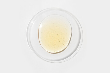 Cosmetic yellow liquid on round glass on light background