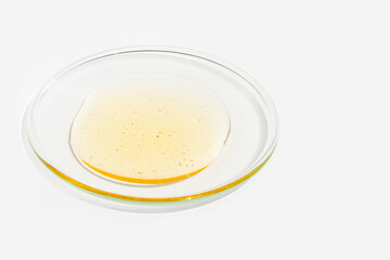 Cosmetic yellow liquid on round glass on light background