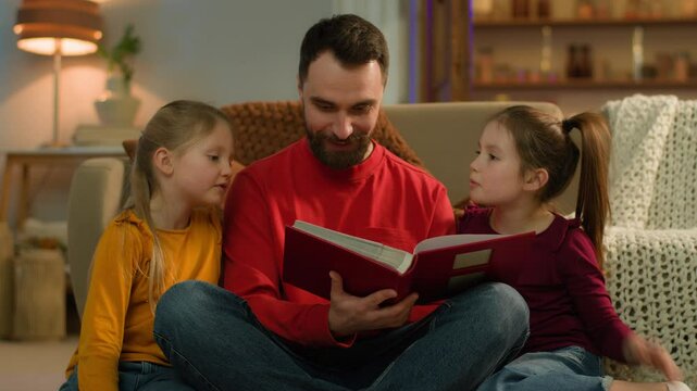 Happy Caucasian family father children little school girls daughters read book together single parent babysitter dad adopted kids siblings smile talk watch pictures photo album at evening home weekend