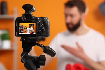 Technology blogger explaining something while recording video at home, focus on camera