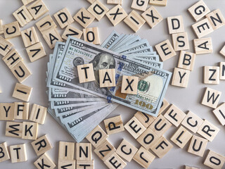 Concept word TAX on wooden blocks with dollar bills. Business  concept