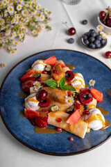 Crepes with Fresh Berries and Toppings, Rolled Thin Pancakes with Cottage Cheese Filling on a Plate