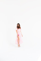 Details of everyday elegant look. Sensual model wearing evening outfit. Pink cocktail dress with puff sleeves shoulders in trendy minimalistic style. Beautiful brunette woman hold pink flower.