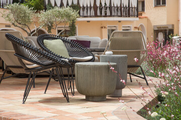 Garden and terrace design or landscaping: Cozy chairs with cushions and tables of an outdoor terrace bar or cafe waiting for guests or tourists in Sardinia, Italy
