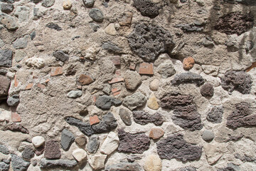House wall with pebble, brick, quarry stones filled with cement, seen in Sardinia, Italy-Natural stone texture for architecture, garden design, landscaping or environmentally sustainable engineering