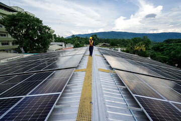 Naklejka premium An Engineer service check installation solar cell on the roof of factory on the morning. Powerful backup power from solar energy, An operator is inspecting solar panels from a tablet on the roof.
