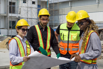 Group of construction worker gathered at a construction site reviewing some plan. Unfinished building, piles of construction material, and a partially constructed structure are in the background