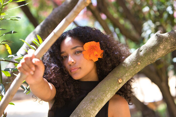 portrait of a beautiful young Latin woman with large, dark eyes and curly hair. The girl wears an...