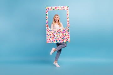 Photo of cheerful positive woman wear stylish white clothes hold frame have fun isolated on blue color background