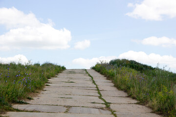 Stone path on the dunes with blue sky and clouds in the background