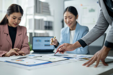 Three women are sitting at a table with a laptop and a few papers