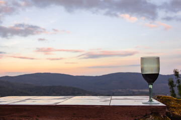 Wine glass resting on tile surface with landscape background at sunset. Copy space.