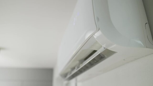 Air conditioner mounted on white wall in modern apartment. Cooling system for comfortable temperature in living room