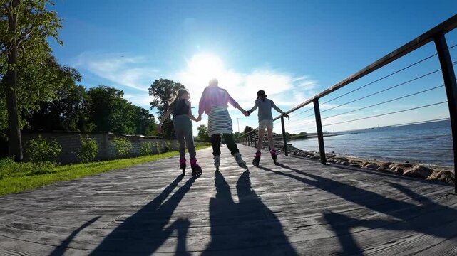 Family rides on rollerblades holding hands on a sunny day. Slow motion