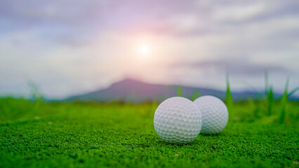 Golf ball on green grass in the evening golf course with sunshine background.