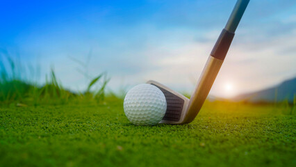 Golf ball and wooden driver on green grass background.
