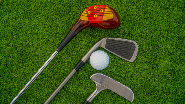 Golf ball and wooden driver on green grass background.