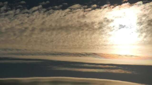 Natural sky background with moving slowly colorful clouds around sunlight - Cloud iridescence, Irisation. Calm sky with pearl colors - optical phenomenon in clouds. Topics: weather, meteorology