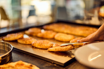 A female baker holding a plate and taking a freshly baked pastry.
