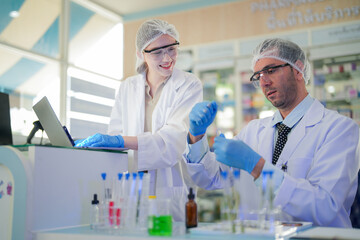 Fototapeta premium scientists perform experiments and record data. people arranges equipment with test tubes and chemicals for producing medicine and biochemistry. man hold tubes of chemical liquids and plant samples.