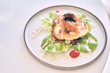 Breakfast of potato pancakes with lightly salted salmon, herbs and cream sauce top view. Delicious vegetable pancakes with salmon on a plate with space to copy. High quality photo