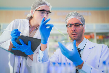 scientists perform experiments and record data. people arranges equipment with test tubes and chemicals for producing medicine and biochemistry. man hold tubes of chemical liquids and plant samples.