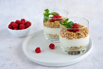 oatmeal with yogurt and raspberry in drinking glasses on the white tray  