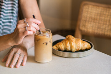 A woman's hand is mixing an iced coffee latte in a coffee shop. Cold summer drink.