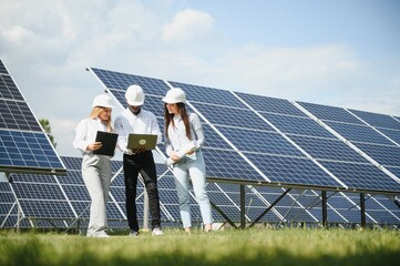 Group of multi ethnic people and safety helmets staring at solar farm.