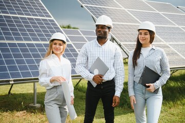 Group of multi ethnic people and safety helmets staring at solar farm.