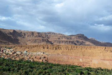Eroded red rock cliffs tower over Todgha River in Todra Gorges, Morocco. A testament to natural beauty and geological time.