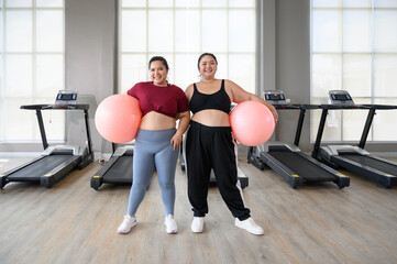 Two overweight women exercise workout in gym. Plus size woman training with fitball. Weight loss workout, healthy lifestyle concept.