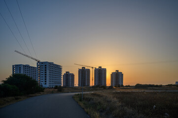 Fototapeta premium Modern multistorey buildings along sea coast with construction cranes in the final stages of construction