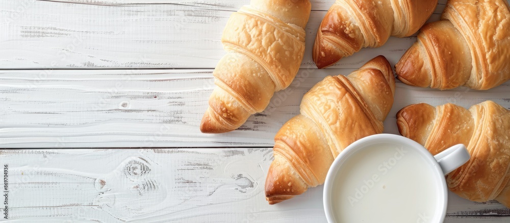 Poster a cup of milk and crescent rolls displayed on a white wooden table, with a clear view from above, id