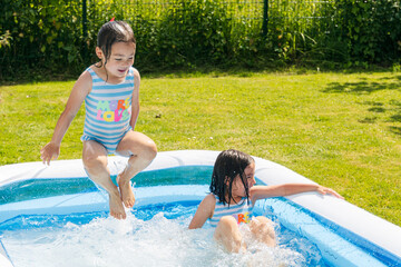 children splashing in an inflatable pool in summer on green grass on a sunny day. vacations, summer fun