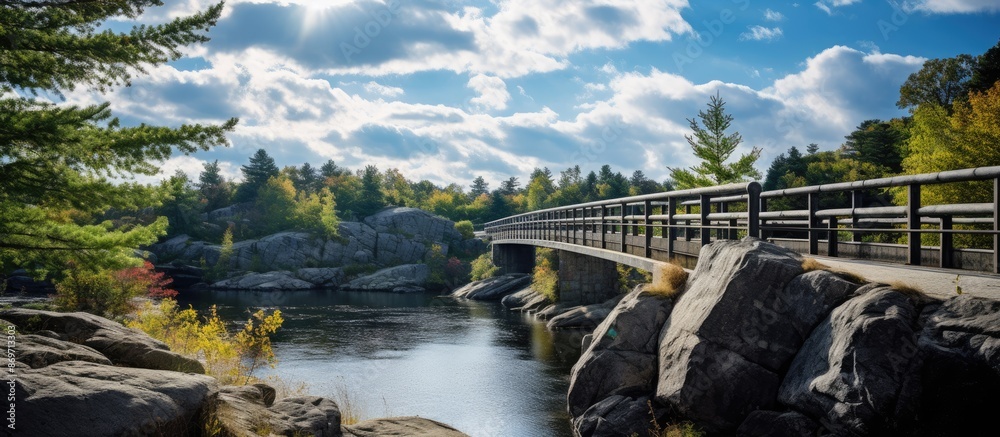 Aufkleber a path leads to a gray granite bridge over a river with metal railings under a sky filled with cloud