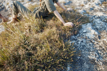 Woman enjoying serene nature vibes sitting on top of grassy hill with hands in the air
