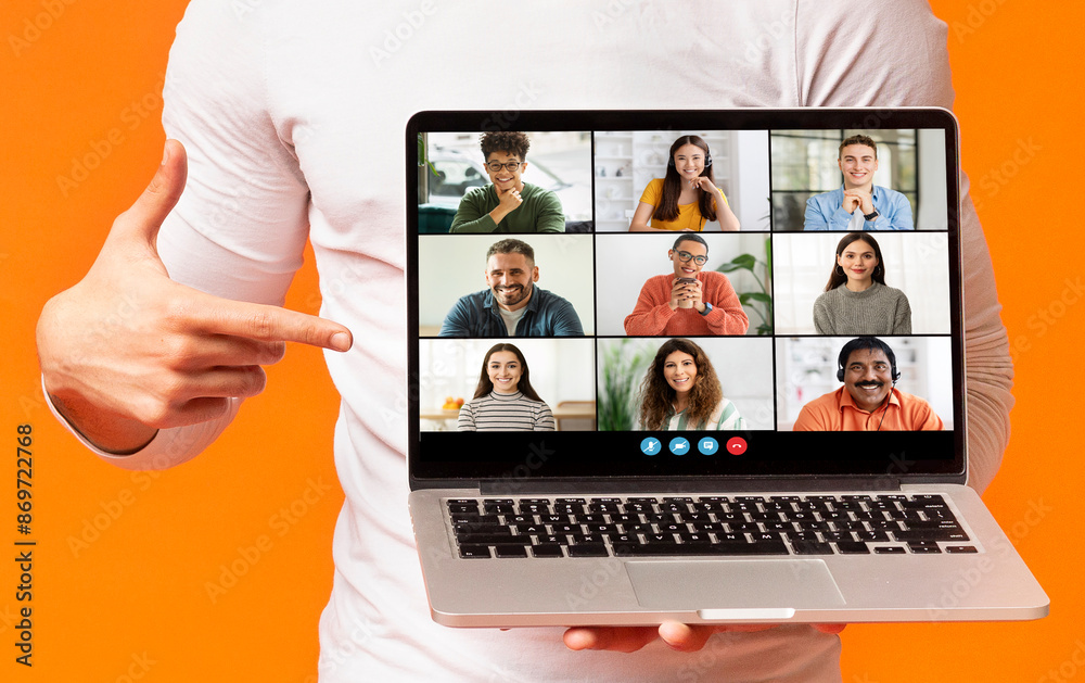 Poster A person is holding a laptop computer in front of them. The laptop screen is displaying a video conference with six different people, orange studio background