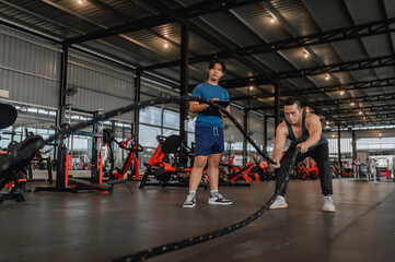 Obraz premium Asian man sitting on a stool with personal trainer,Hire a professional trainer to teach weight training,body and healthy cardio sports workout