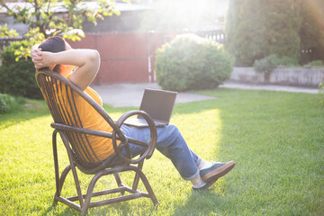 Fototapeta premium Woman using laptop while sitting in the yard and working from home.