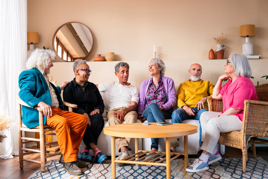 Group of happy senior friends bonding at home for dinner party - Cheerful and youthful old mature multiethnic people having fun