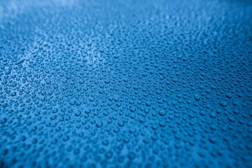 Perfect round water drops on blue car body. Hydrophobic effect after use car ceramic coating