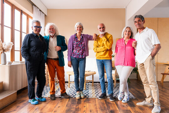 Group of happy senior friends bonding at home for dinner party - Cheerful and youthful old mature multiethnic people having fun