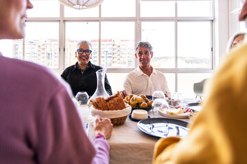 Group of happy senior friends bonding at home for dinner party - Cheerful and youthful old mature multiethnic people having fun