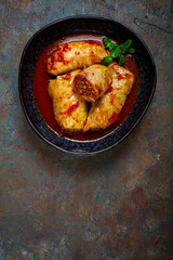 Stuffed cabbage rolls with minced meat, in tomato sauce, top view, without people, in the spotlight.